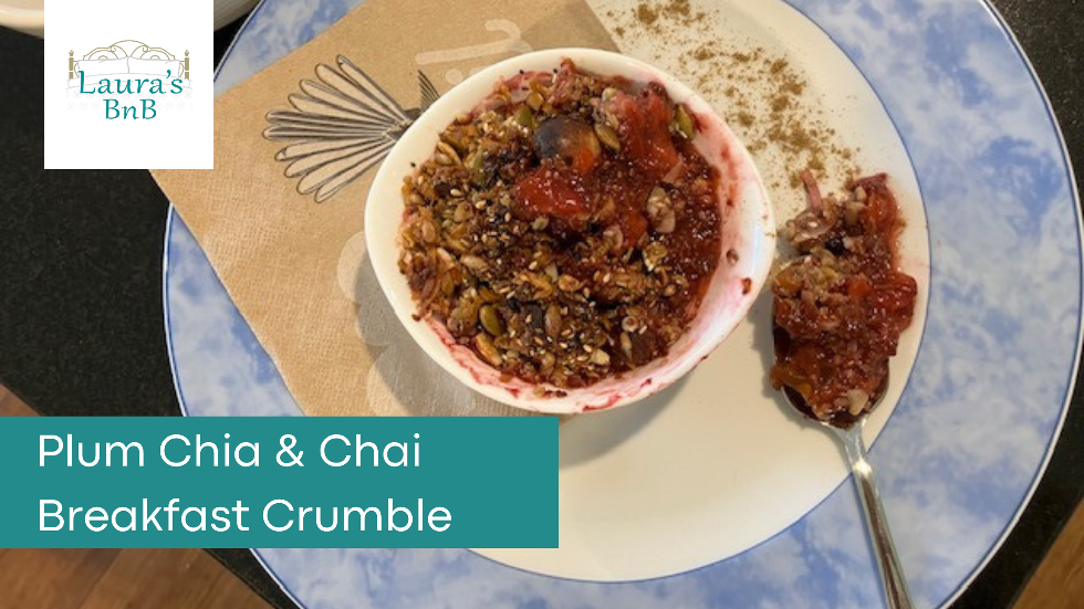 Photo of a ramekin dish containing plum, chia and chai breakfast crumble. Laura's BnB logo is at the top left.